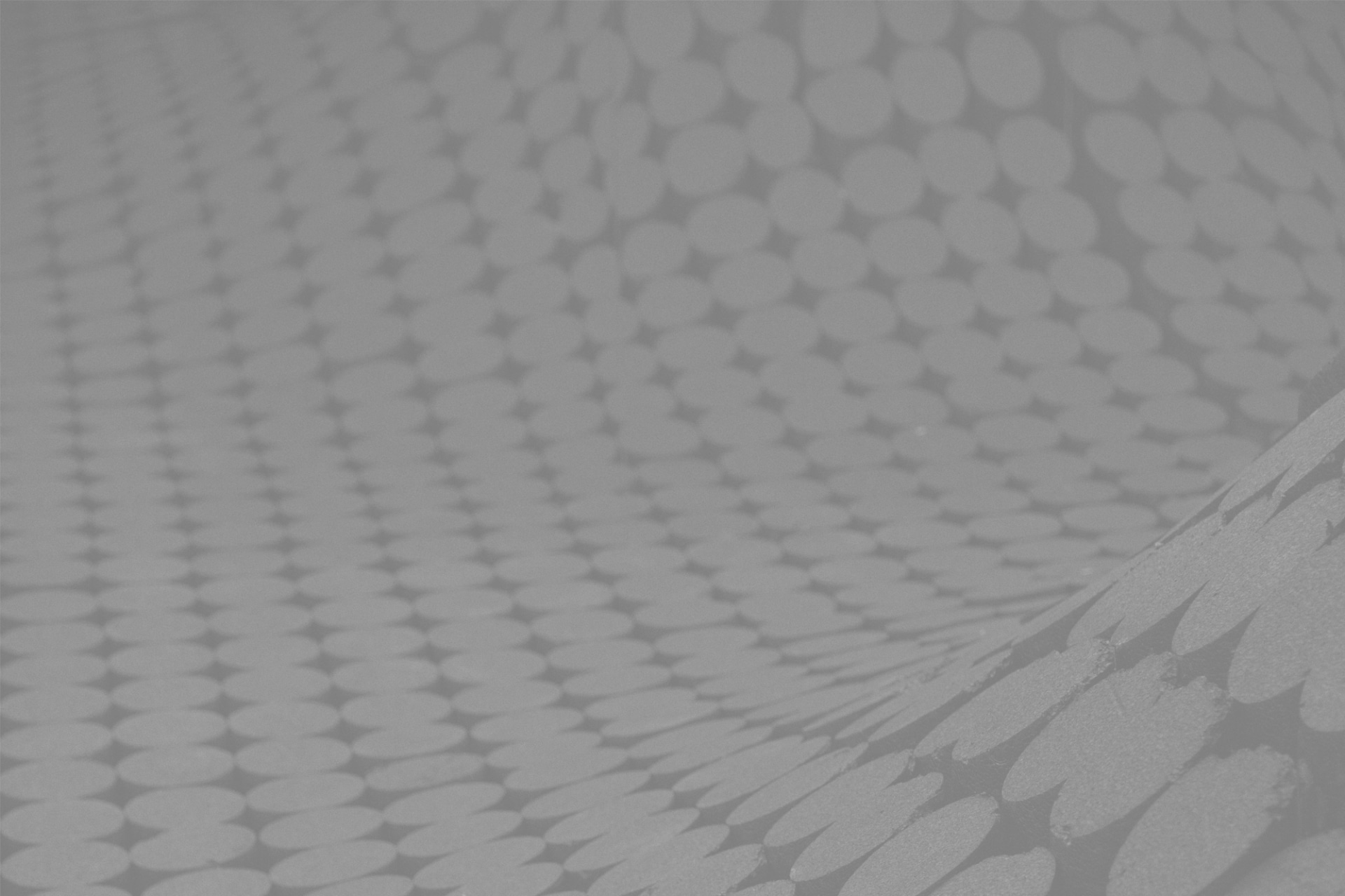 Gros plan d'une surface recouverte d'un motif de points circulaires uniformes en relief. Les points créent une illusion d'optique de vagues et de courbes superposées en trois dimensions. L'image est en niveaux de gris, ce qui lui donne une apparence texturée et abstraite.