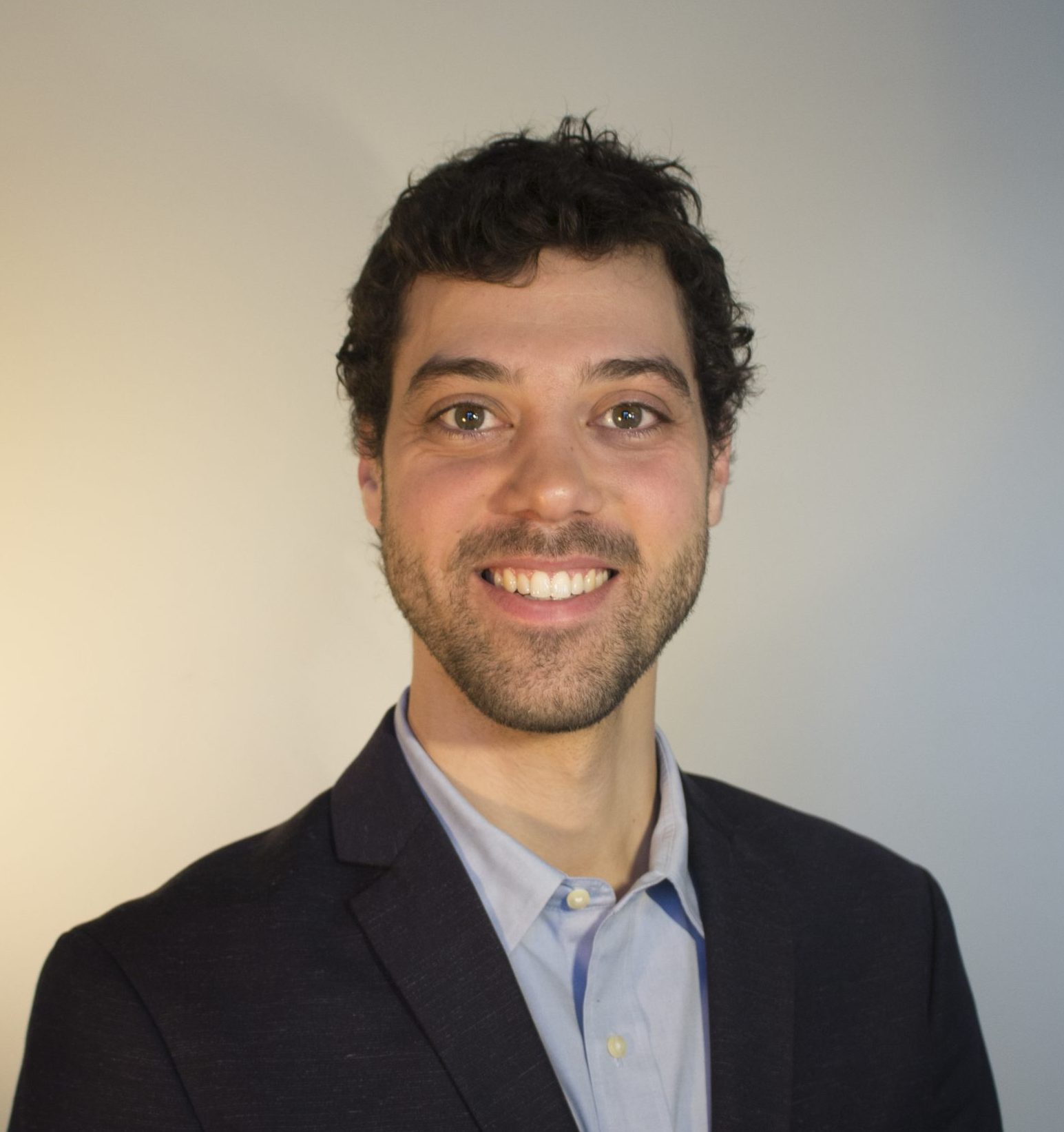 Florent Giordani_temp Un homme portant un veston noir et une chemise bleu sans cravate.